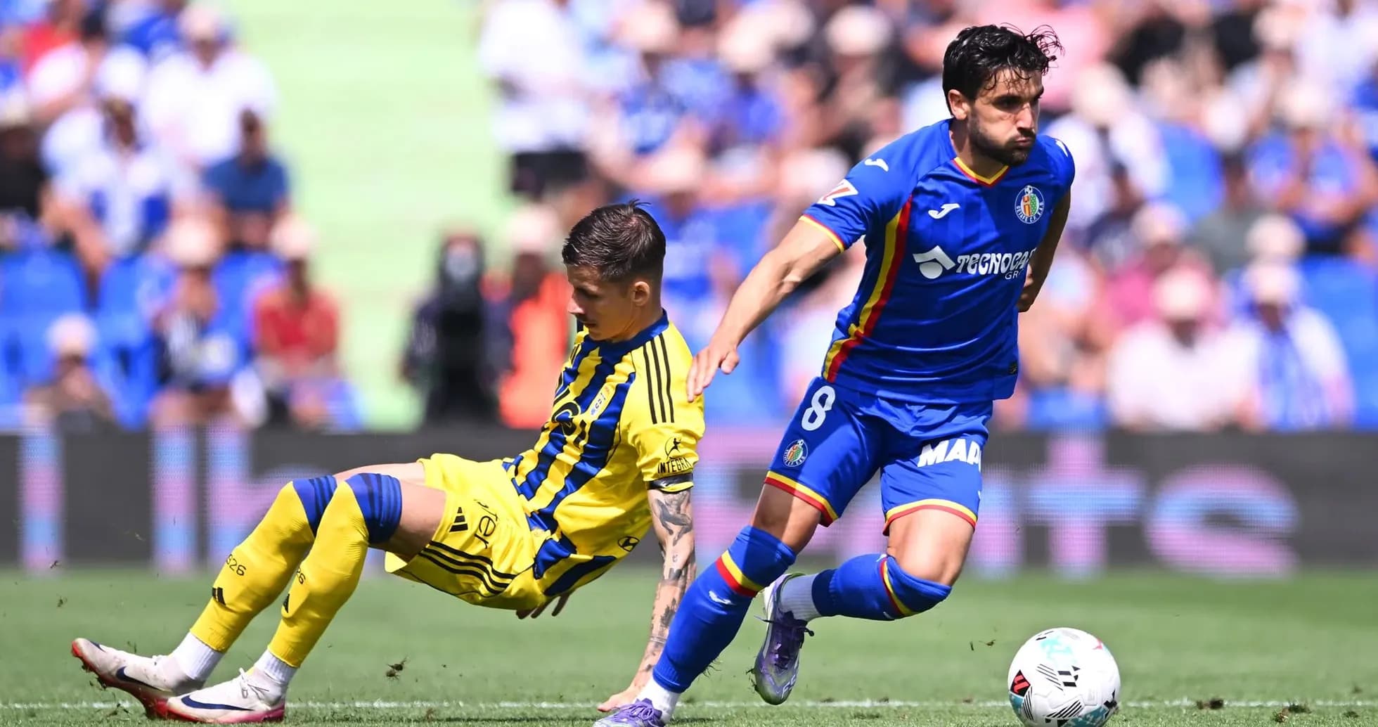 Getafe player evading Oviedo tackle during match Getafe player evading Oviedo tackle during match