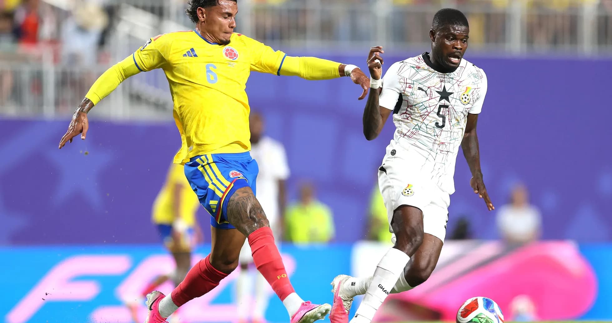 Colombia player tackling Ghana opponent during match Colombia player tackling Ghana opponent during match