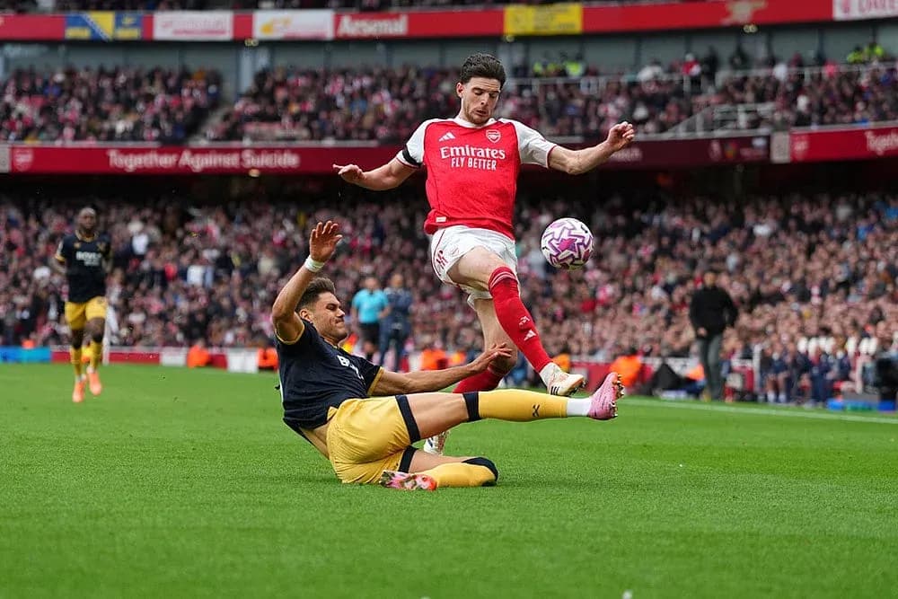 Arsenal player evading tackle during match Arsenal player evading tackle during match