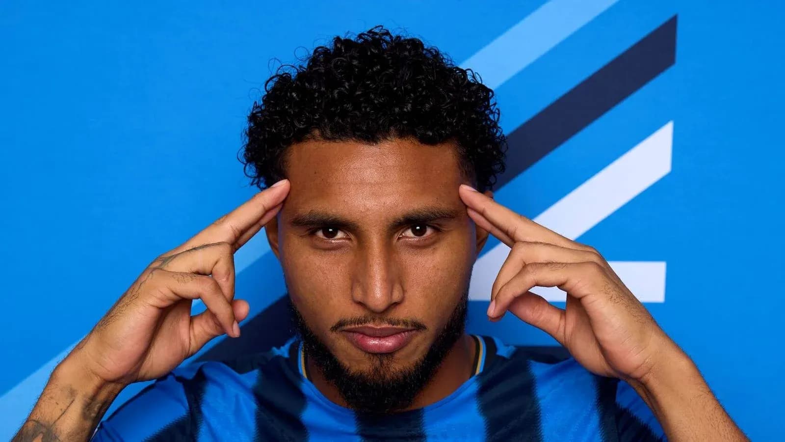 Player posing with hands on temples against blue background Player posing with hands on temples against blue background