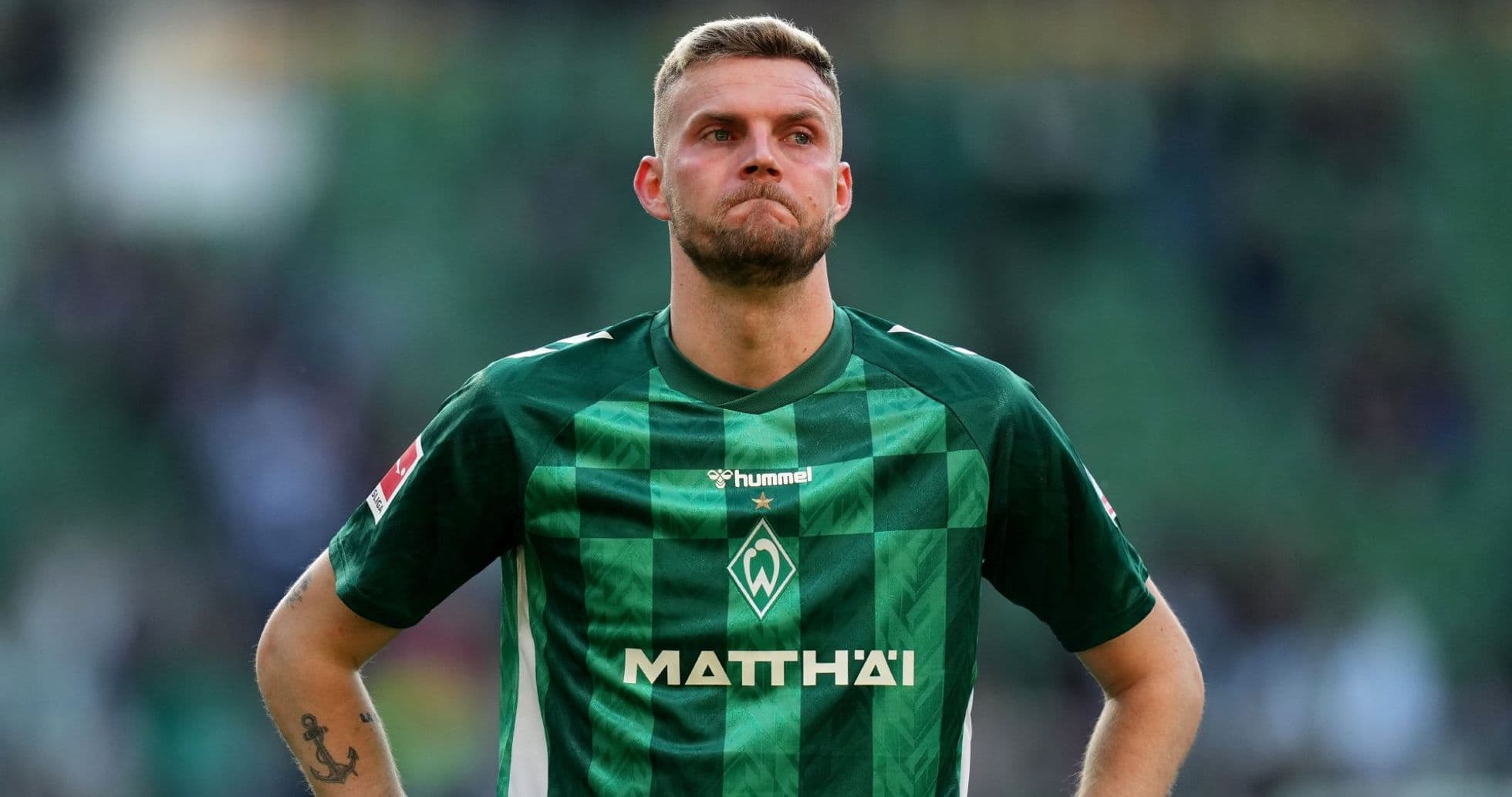 Player in green jersey during match at stadium Player in green jersey during match at stadium
