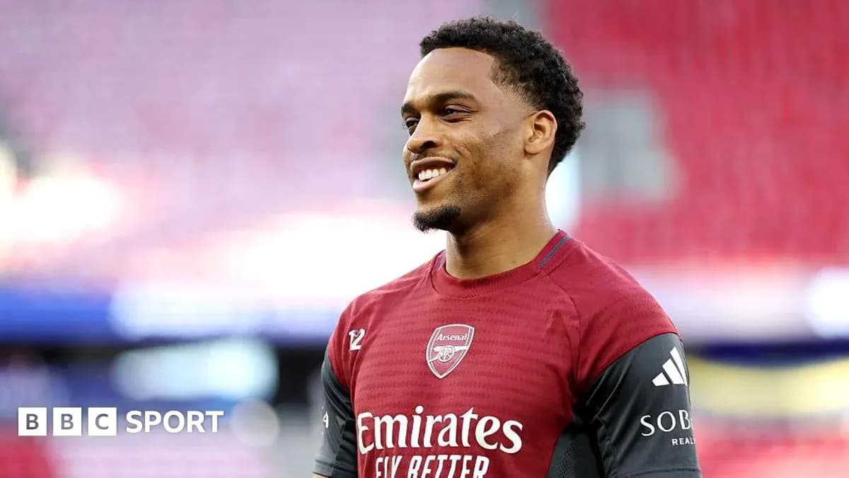 Player in Arsenal training kit smiling on pitch Player in Arsenal training kit smiling on pitch