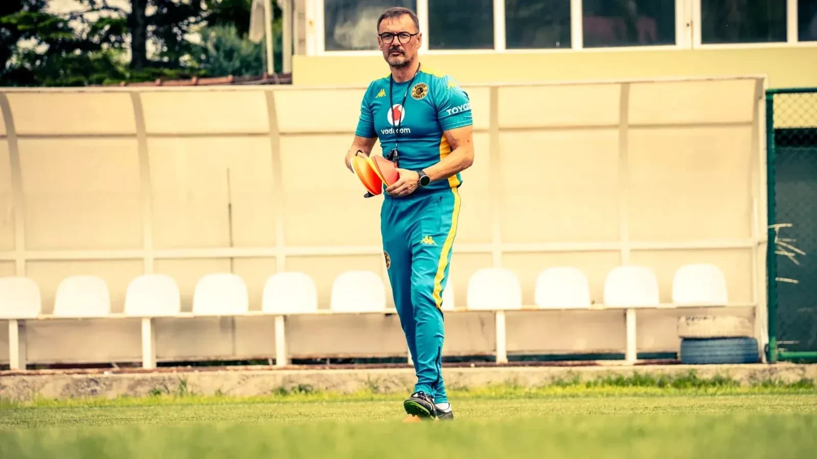 Coach walking on field holding training cones Coach walking on field holding training cones