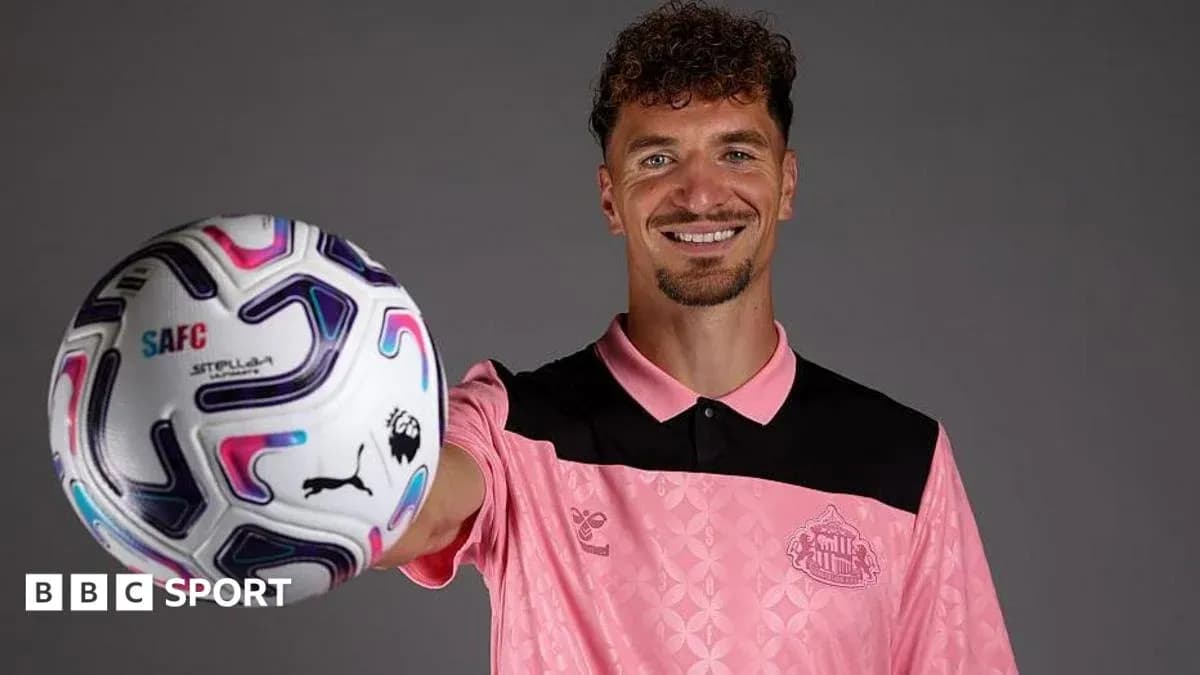 Player holding a football and smiling at camera Player holding a football and smiling at camera