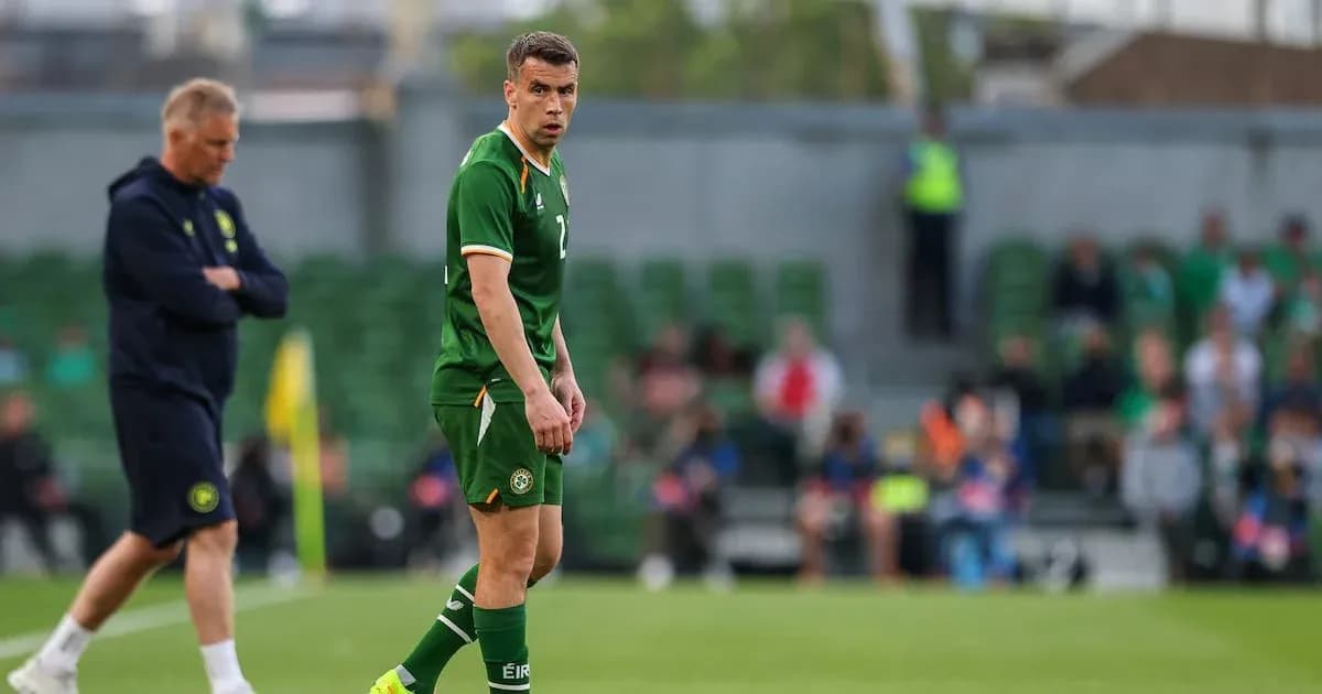 Player in green kit during match, coach in background Player in green kit during match, coach in background