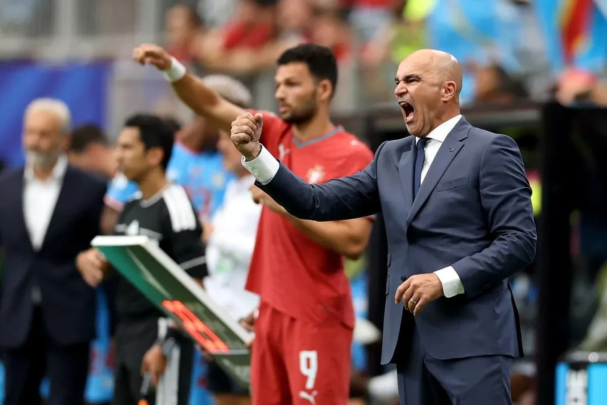 Coach celebrating while players observe from sidelines Coach celebrating while players observe from sidelines
