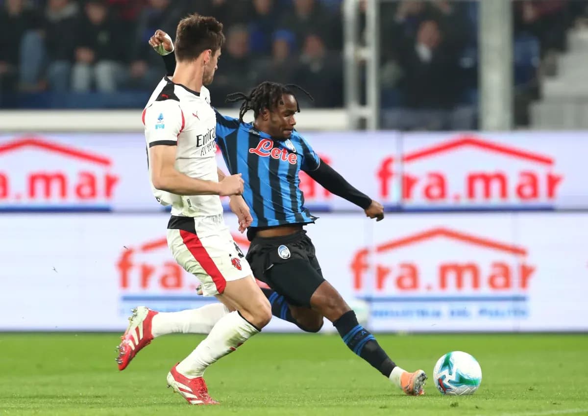 AC Milan player challenging Atalanta opponent AC Milan player challenging Atalanta opponent